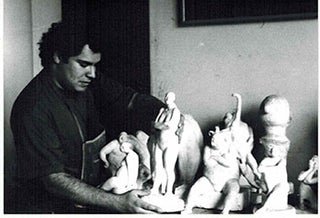 Item #51-0620 Photograph of the Artist with sculptures holding la Mujer del Circo. Armando Romero