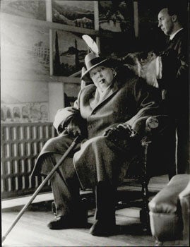 Item #51-5202 Sir Winston Churchill sitting in an armchair in an overcoat with cane, cigar and...