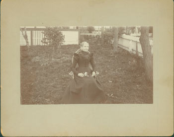 Item #63-2642 Photograph of seated elderly lady in black dress, holding flowers in her lap. 19th Century American Photographer.