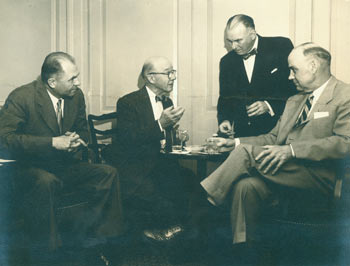 Item #63-2675 Photographic print of three men [including Arthur Meier Schlesinger Sr.?] seated, one man standing. 20th Century American Photographer.