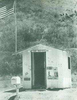 [Rialto, CA Photography Studio] - Modern Print of a Black and White Photograph of the de Luz Post Office, a Tiny Shack with Posters for the World's Fair, the Wpa, Preventing Forest Fires, and Wanted Men