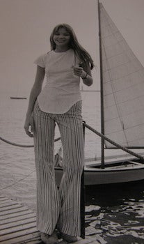 Item #68-0457 Blonde woman on dock with sailboat behind her. Photograph from the 1970 Cannes...