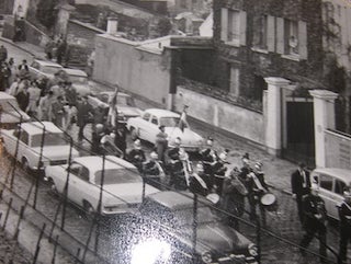 Item #68-4281 B&W Photo of procession led down a street, with a marching band at the head....